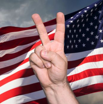 Patriotic concept.  Man hand showing the sign of victory and peace against of USA flag

