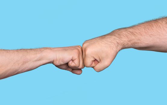 Two men bumping fists isolated on blue background