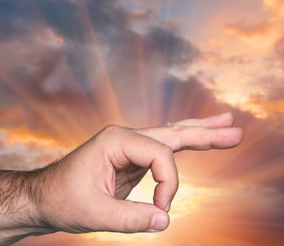 Hand OK sign against sunset sky with sunbeams