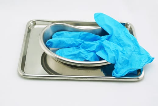 Medical devices include emesis basin tray and glove resting on a white background.                             