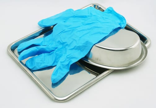 Medical devices include emesis basin tray and glove resting on a white background.                               