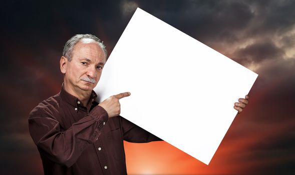 An elderly man holding a blank billboard on dramatic dark sky background