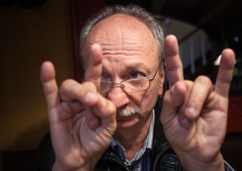 Portrait of a pensive old man gesturing at the cafe