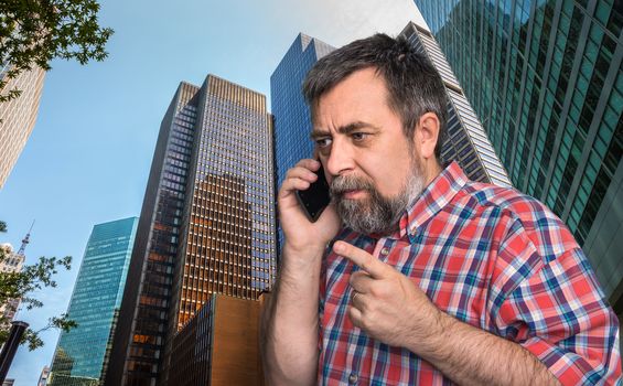 Middle-aged businessman talking on mobile phone in the megalopolis