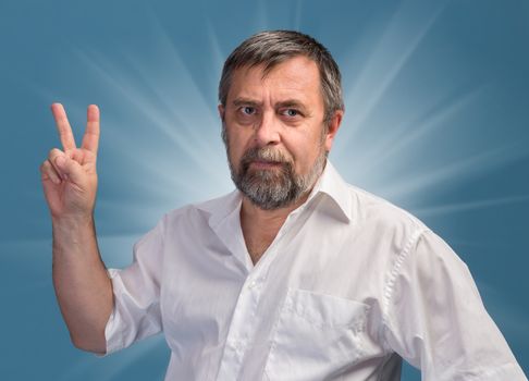 Middle-aged man in a white shirt showing victory sign on blue background
