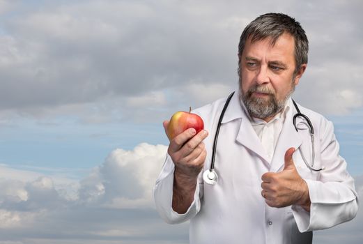 Good diet and healthy lifestyle concept. Doctor advises apple for healthy eating against the sky with clouds