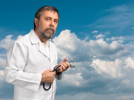 Health care concept. Medical doctor with stethoscope against blue cloudy sky