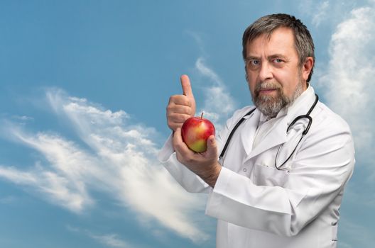 Good diet and healthy lifestyle concept. Doctor advises apple for healthy eating against the blue sky with clouds