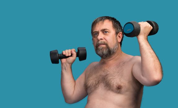 Elderly man exercising with dumbbells isolated on blue background