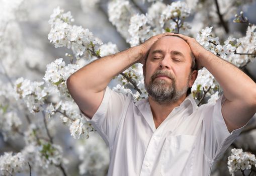 Middle-aged man enjoying nature in the flowered garden