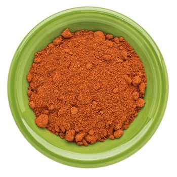 organic paprika powder on an isolated green ceramic bowl, top view