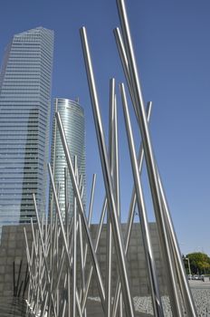 Steel sculpture in front of the Crystal and the Space Towers in the Four Towers Business Area, Madrid, Spain.  
The Crystal tower was designed by Pelli and the  SpaceTower by  by Henry N. Cobb