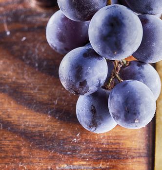 Black grape over wooden barrell, square image