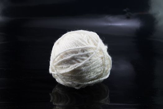 The white ball of wool thread on a black background,  textile