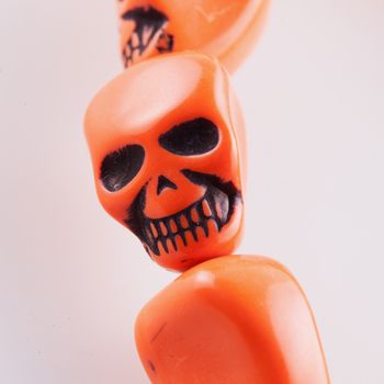 Orange grinning skull in a bracelet, over white background