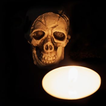 Skull behind a candle in black background