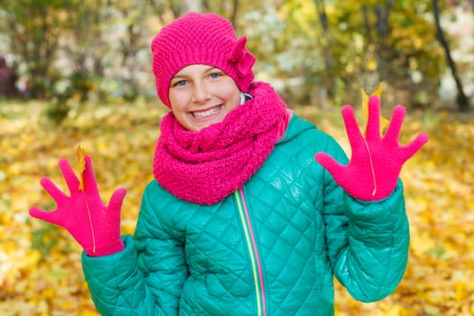 Portrait of Adorable cute girl with autumn leaves in the beauty park