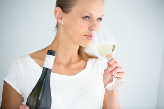 Gorgeous young woman with a glass of wine, smelling the lovely drink, savouring every sip (shallow DOF; color toned image)