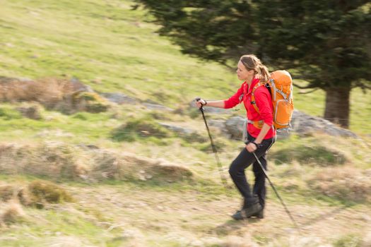 Pretty, young woman hiking in mountains (motion blurred image)