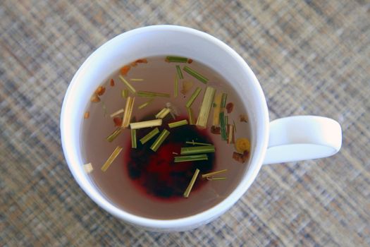 white cup of tea with pink of various herbs