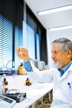 Senior male researcher carrying out scientific research in a lab (shallow DOF; color toned image)