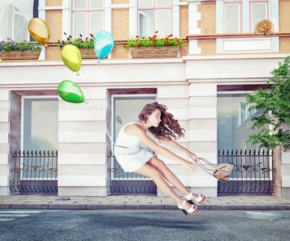 Balloons fly with young beautiful girl. Creative concept