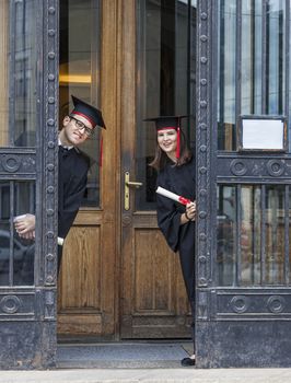 Young couple in the graduation day having fun at the gate of the University.