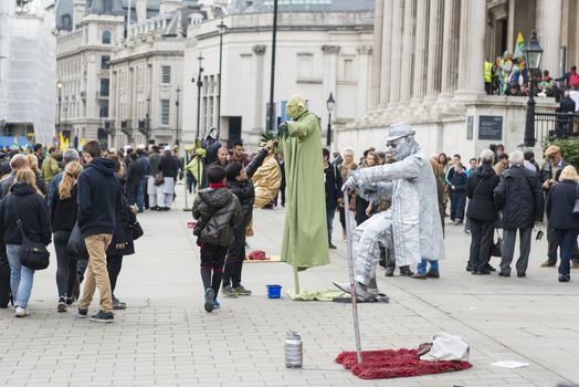LONDON, UK - OCTOBER 26: Street artists levitating in busy Trafalgar Square. In central London, street artists must obtain a permit in order to perform in public spaces. October 26, 2014 in London.