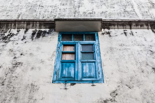 Vivid blue wooden window and grunge wall