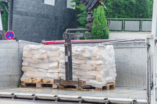 Pallets with sandstones are delivered and unloaded from a truck.