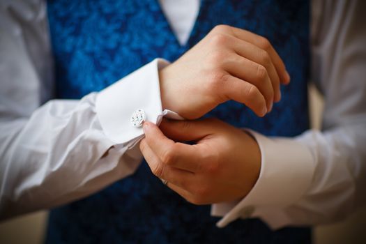 Bridegroom preparing for the wedding, straightens his shirt sleeves