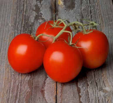 Four Ripe Raw Grape Tomatoes with Stems isolated on Rustic Wooden background