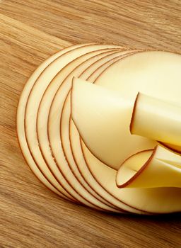 Stack of Sliced Delicious Smoked Cheese isolated on Wooden Cutting Board