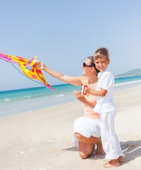 Summer vacation - Cute boy with his mother flying kite beach outdoor.