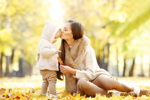 Beautiful young mother and her daughter in autumn park