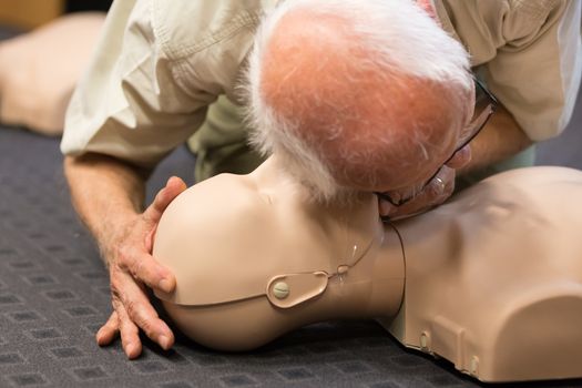 Seniror first aid student practitcing CPR on a dummy. 