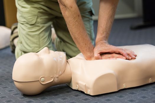 A group of adult education students practitcing CPR chest compressioon on a dummy. 