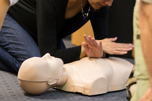 A group of adult education students practitcing CPR chest compressioon on a dummy. 