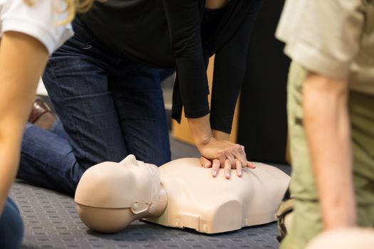 A group of adult education students practitcing CPR chest compressioon on a dummy. 