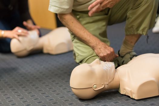 Seniror first aid student practitcing CPR on a dummy. 