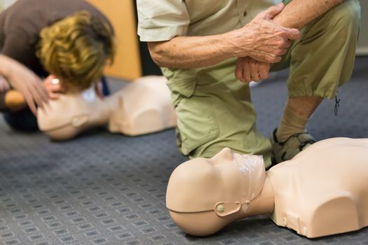 Seniror first aid student practitcing CPR on a dummy. 