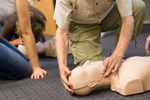 Seniror first aid student practitcing CPR on a dummy. 