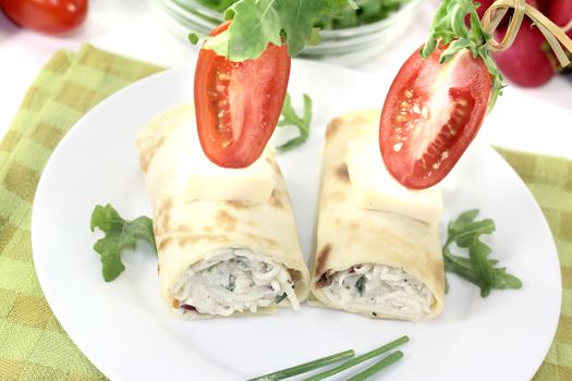 stuffed cheese crepe rolls with tomatoes on a light background