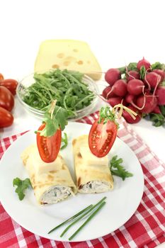 stuffed cheese crepe rolls with chives on a light background
