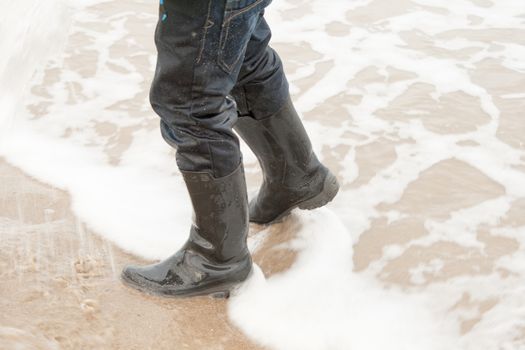 child walking in the sea with boots