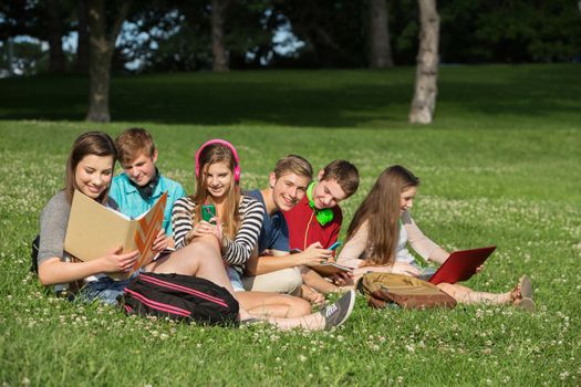 Cheerful students with books and laptop working outdoors