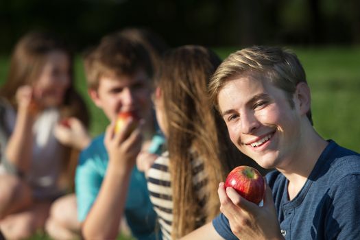 Smiling Caucasian teenager hold red delicious apple 