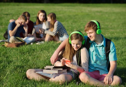 Teen students sitting and listening to mp3 player together