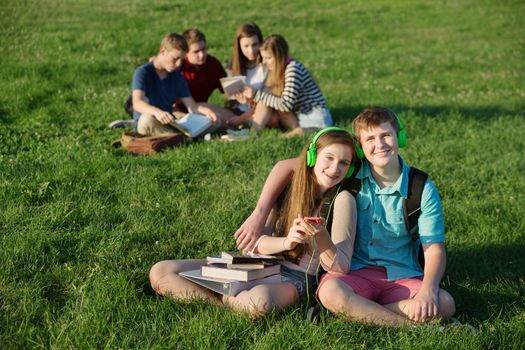 Cheerful European couple with earphones and cell phone outdoors