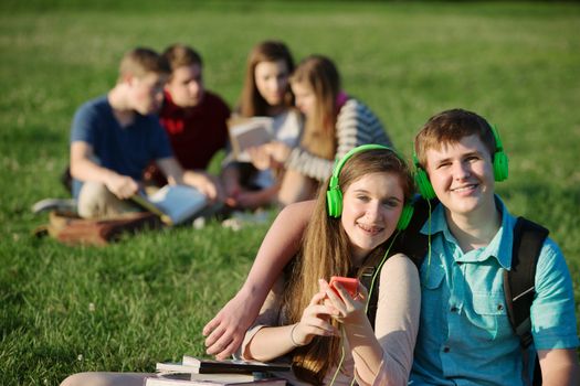 Two teenage students sitting outdoors with earphones
